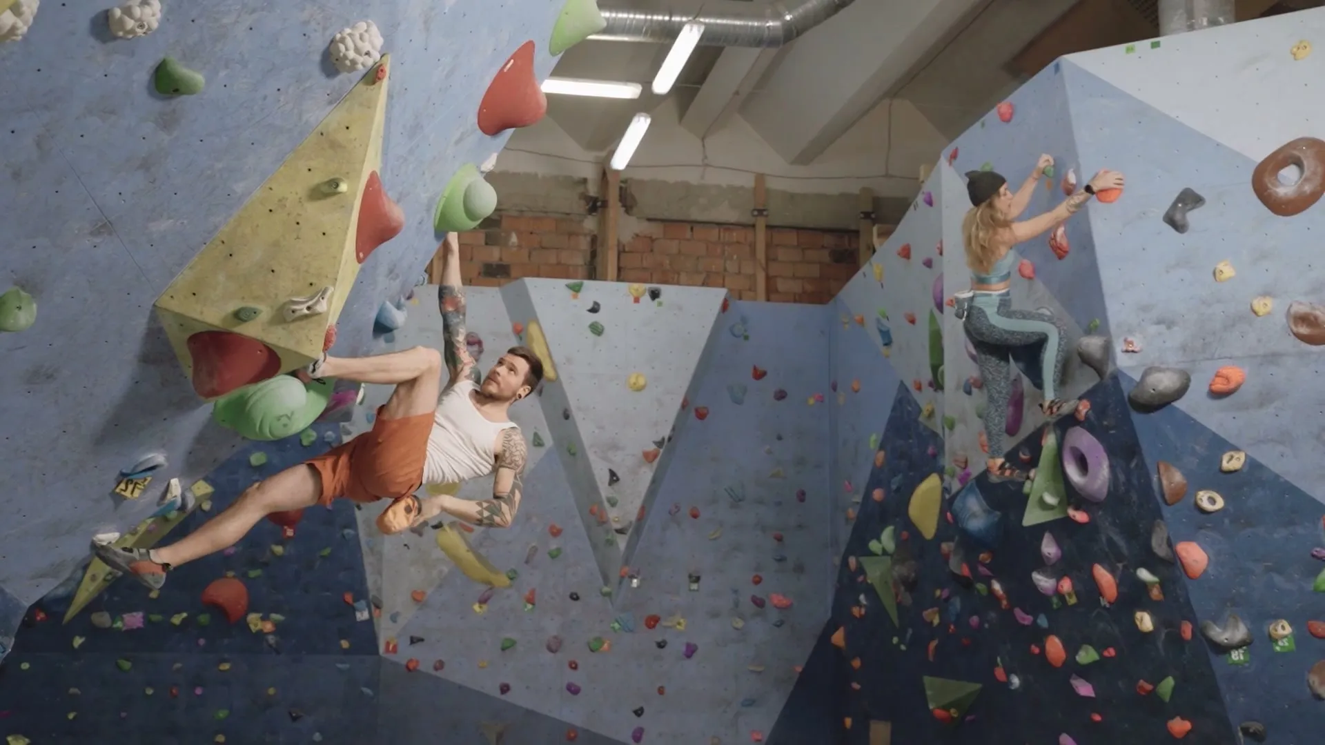 Kletterer in einer Boulderhalle an einer bunten Wand