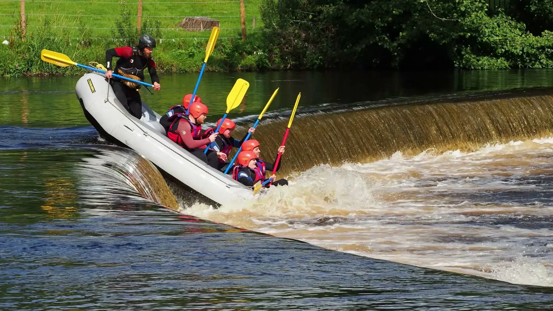 Rafting-Gruppe fährt mit dem Schlauchboot über ein Wehr