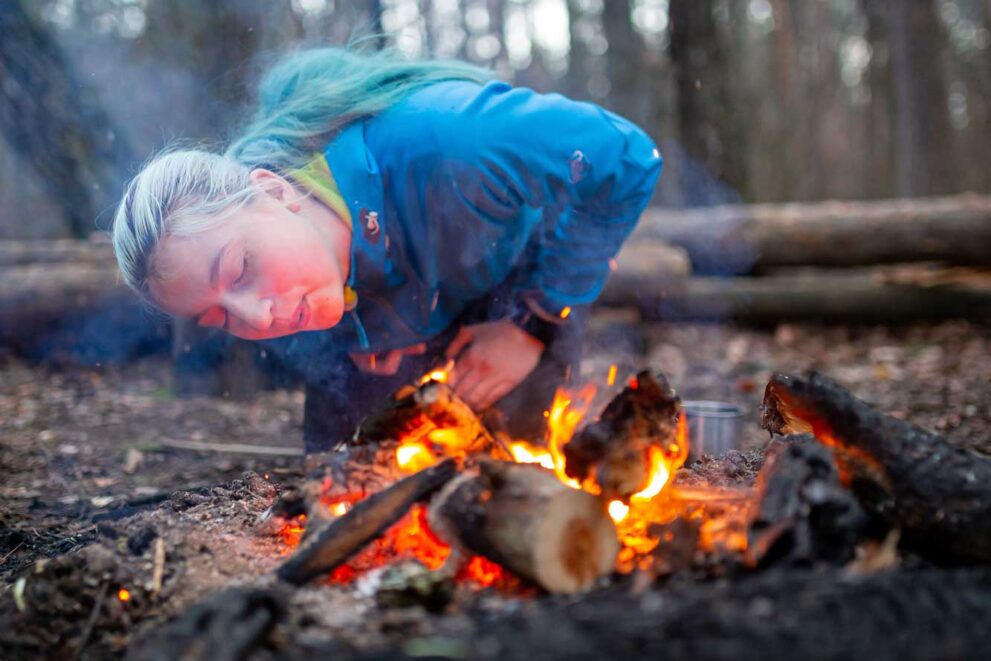 Teilnehmerin eines Wildniskurses entfacht ein Lagerfeuer